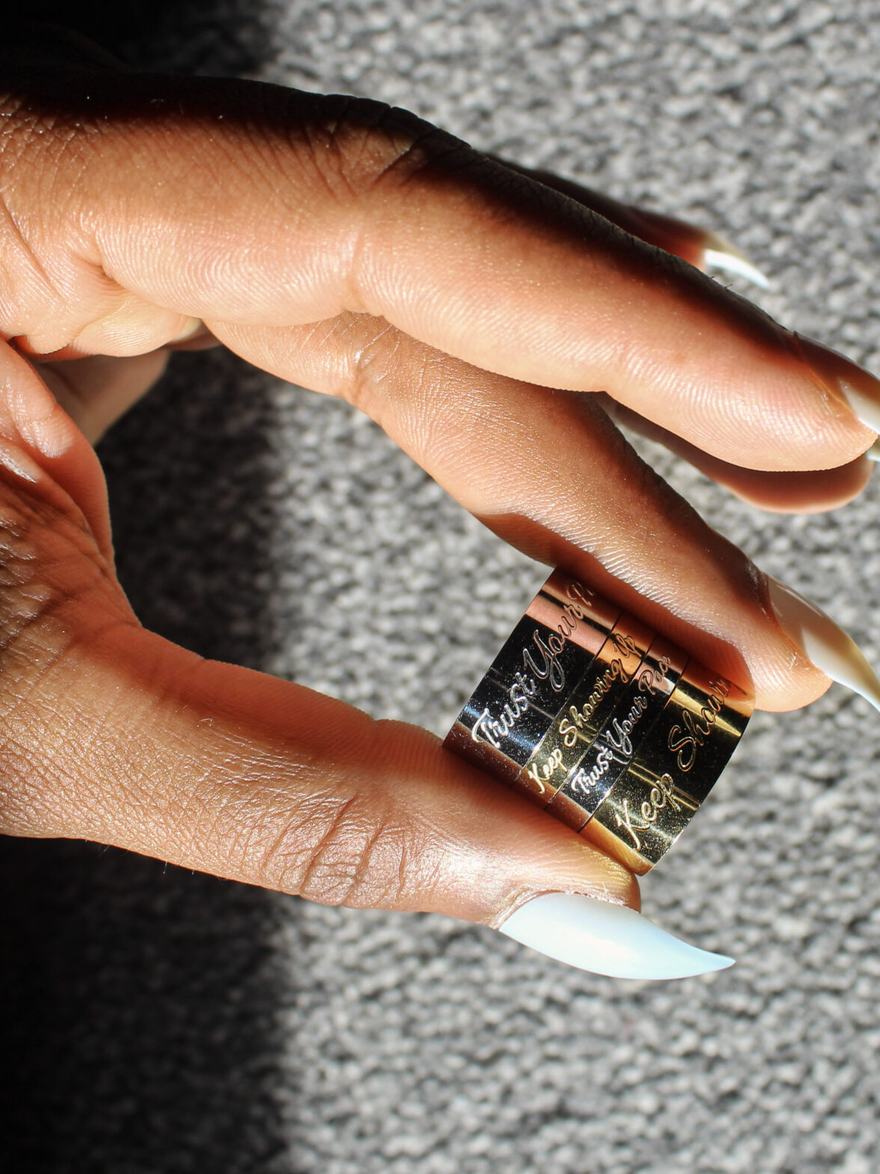 Three engraved rings held between finger and thumb in low afternoon light.