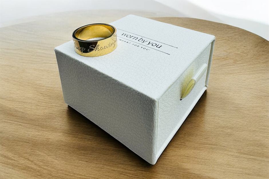 A gold band resting on its gift box.
