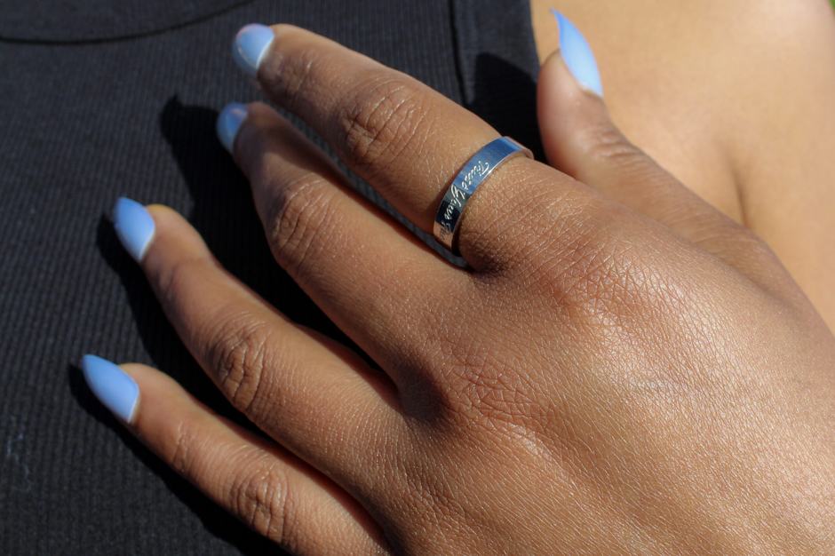 A hand resting on the chest, wearing a silver band.