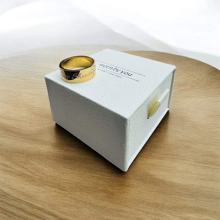 Keep Showing Up ring in gold, resting on its worn by you box.