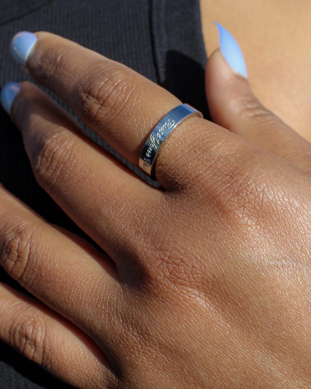 A hand resting against the chest, wearing a Begin Again band.