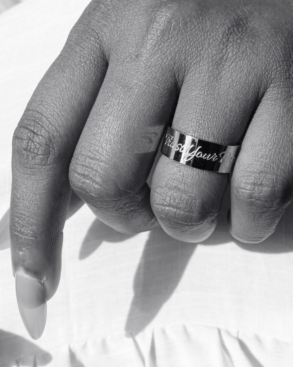 A silver Trust Your Pace band, photographed in black and white.