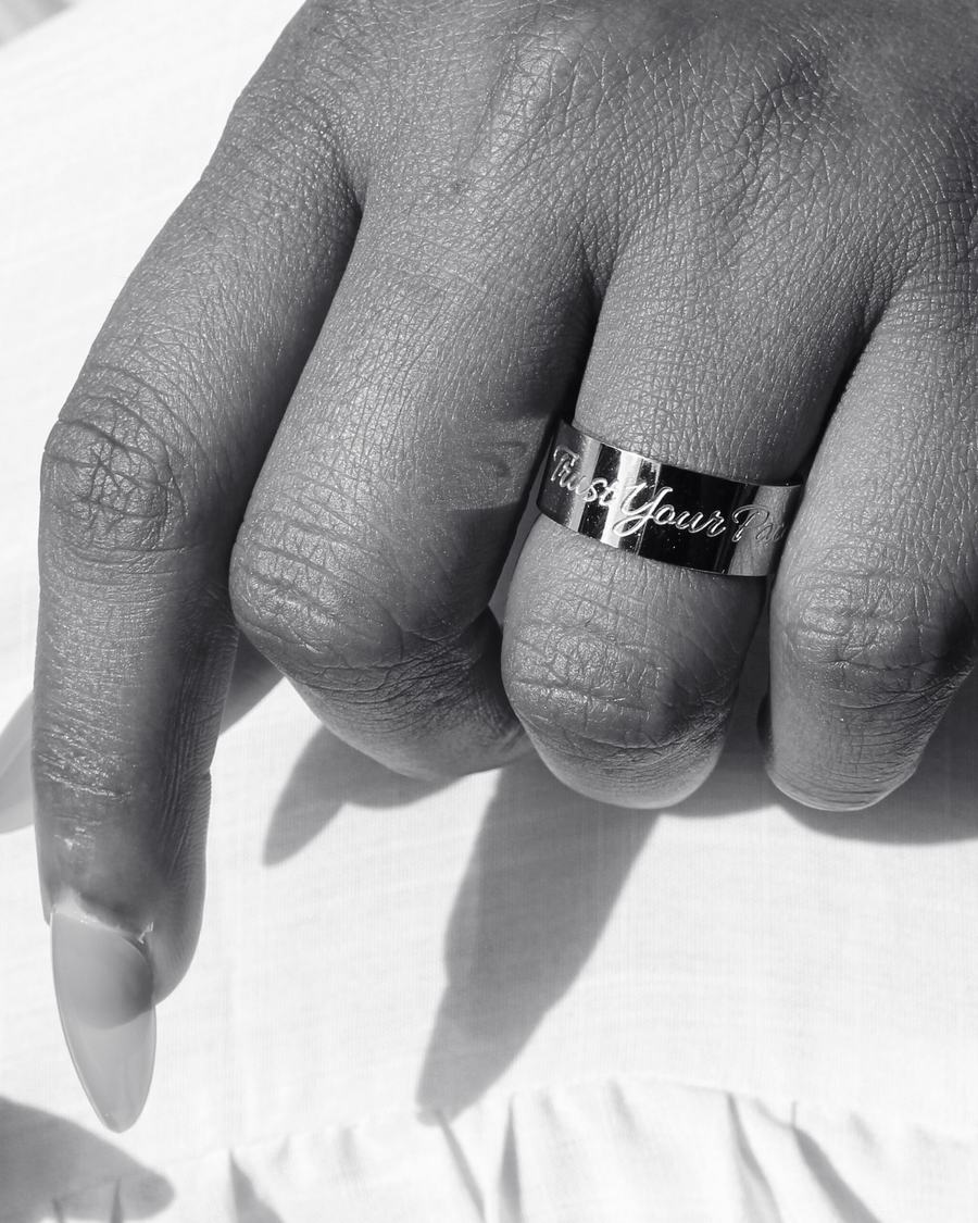 A silver engraved band in close-up, black and white.